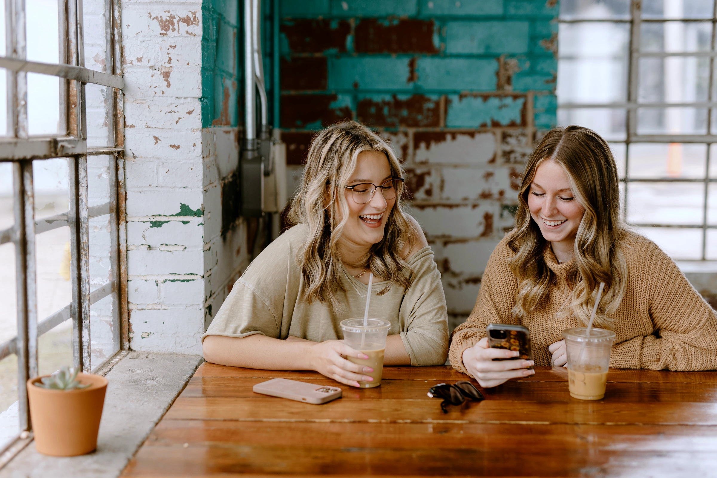 Deux amies regardent un téléphone à une table de café